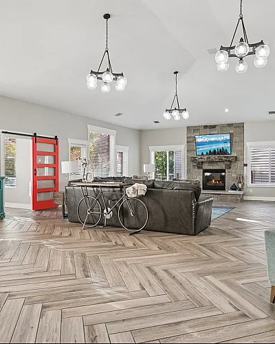 Elegant living room with herringbone wood flooring, vibrant red sliding barn door, and cozy stone fireplace, perfect for modern comfort and style.