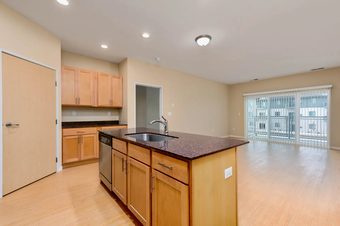Modern open-concept kitchen and living area with granite countertops, stylish cabinetry, and large sliding glass doors for natural light.
