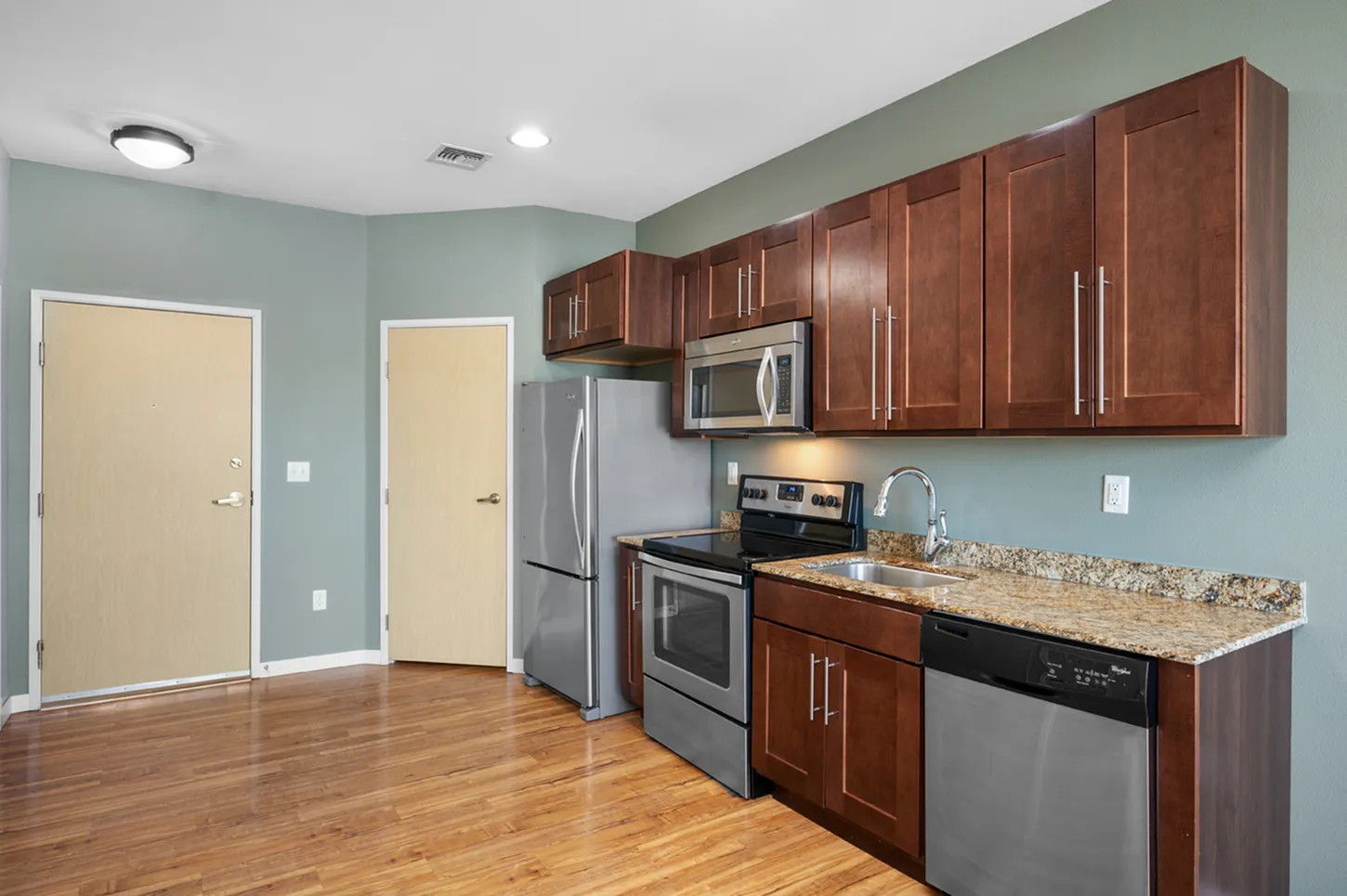 Modern kitchen with sleek stainless steel appliances, rich wood cabinetry, and elegant granite countertops.