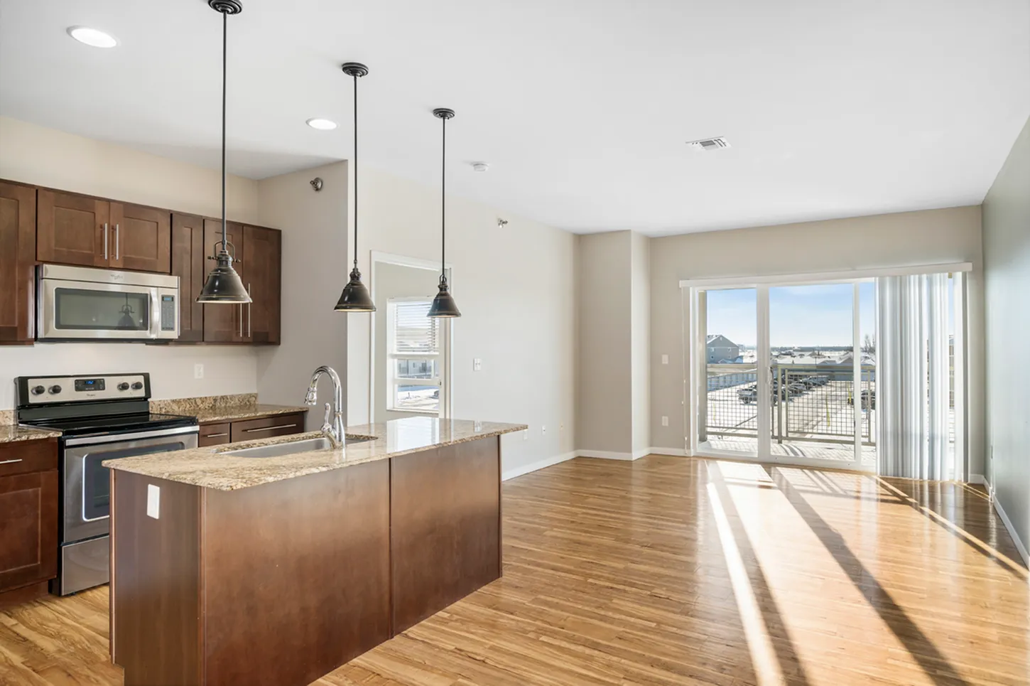Modern open-concept kitchen and living area with sleek appliances, elegant wooden cabinetry, and large windows offering abundant natural light.