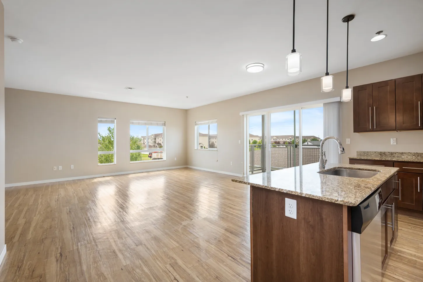 Bright open-plan living space with large windows, modern hardwood floors, and stylish kitchen island with granite countertops.