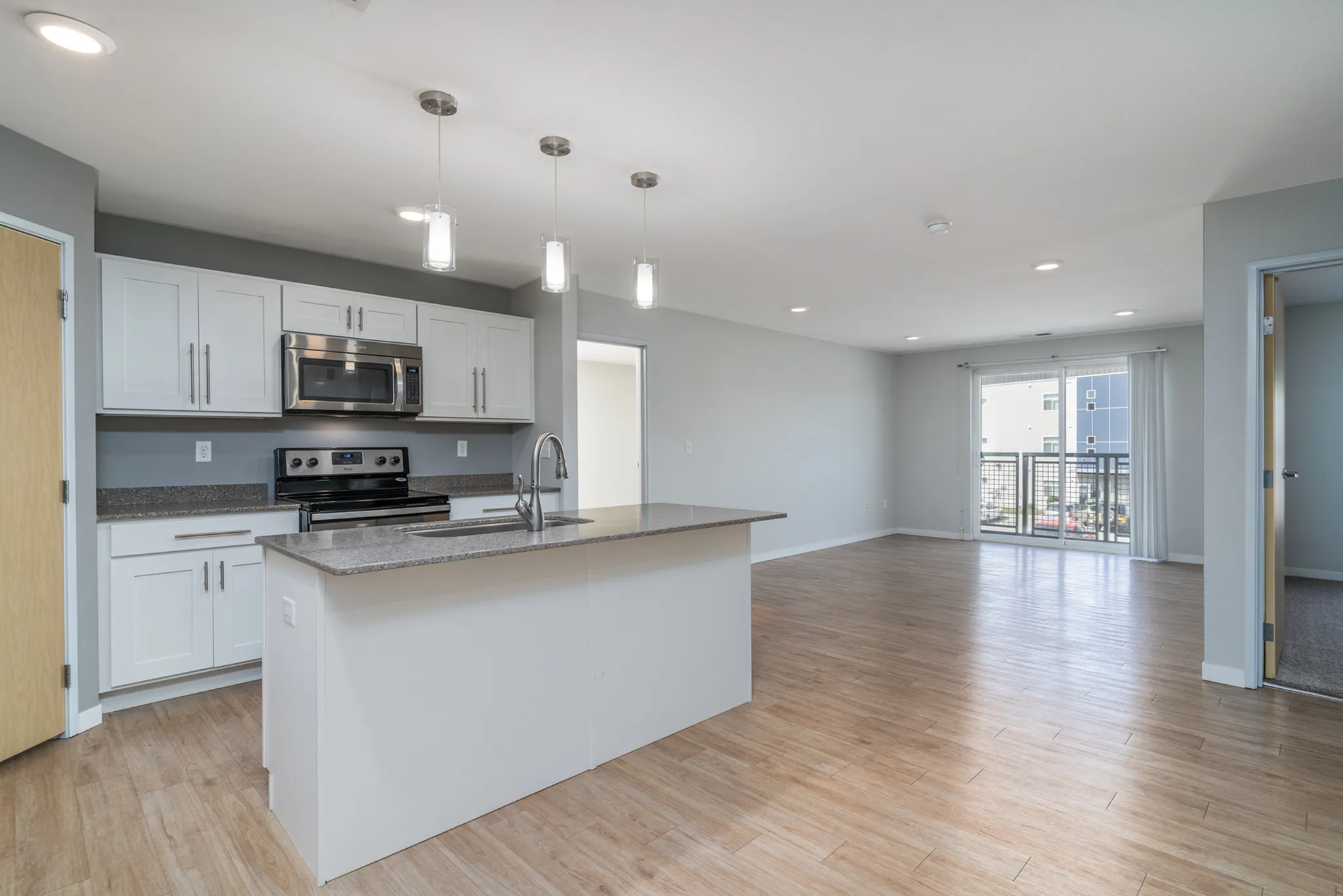 Modern open-plan kitchen and living area featuring sleek stainless-steel appliances, stylish cabinetry, and elegant pendant lighting.