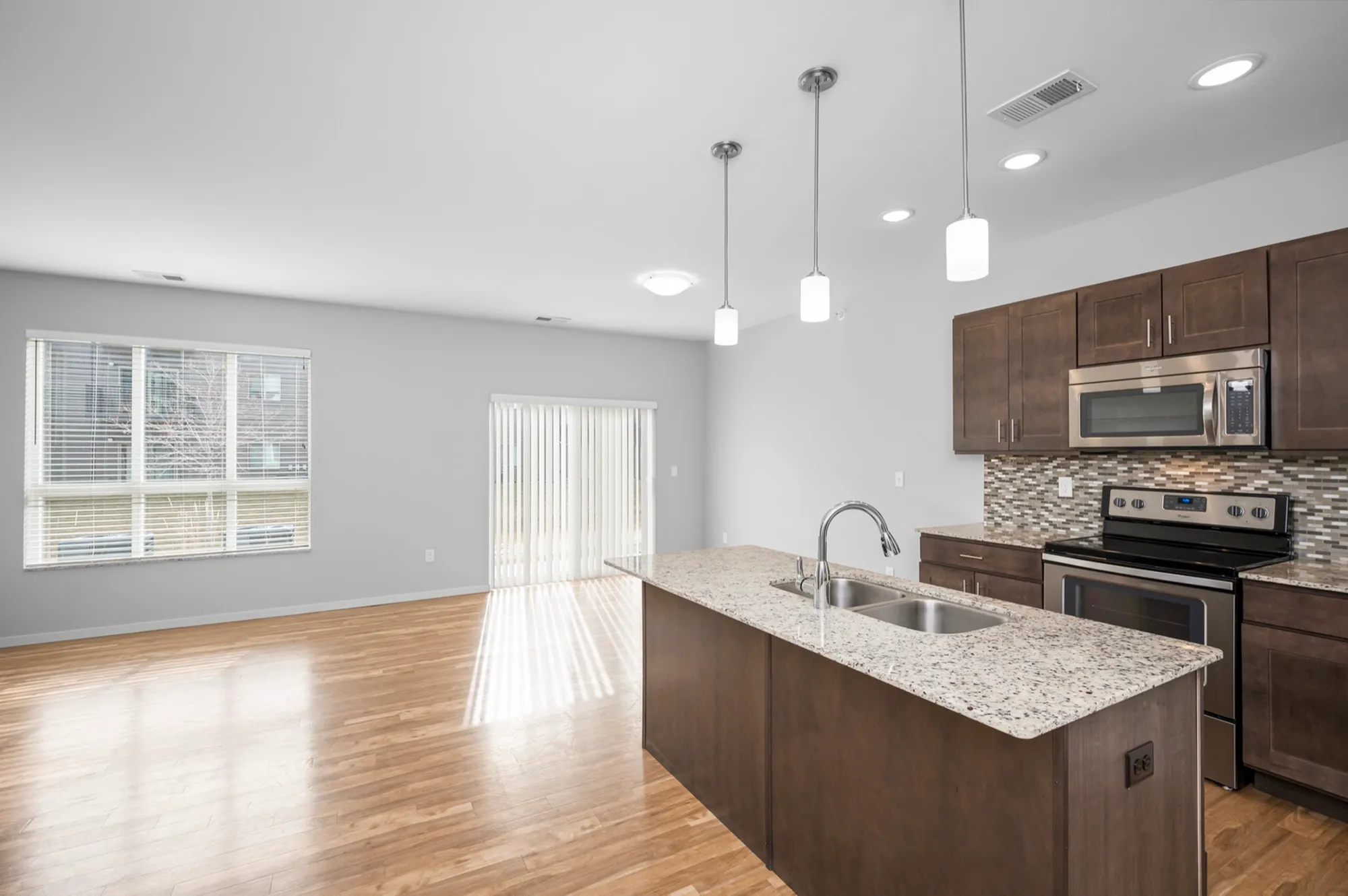 Modern open-concept kitchen with sleek granite countertops, stainless steel appliances, and large windows providing ample natural light.