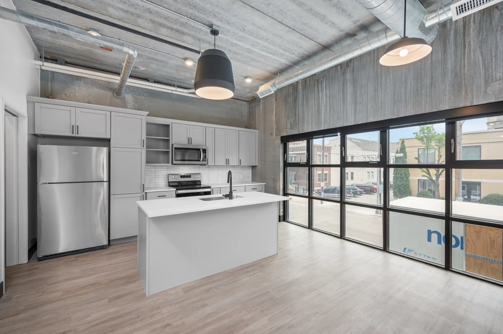 Chic urban kitchen with modern appliances, sleek cabinets, and expansive windows offering abundant natural light.