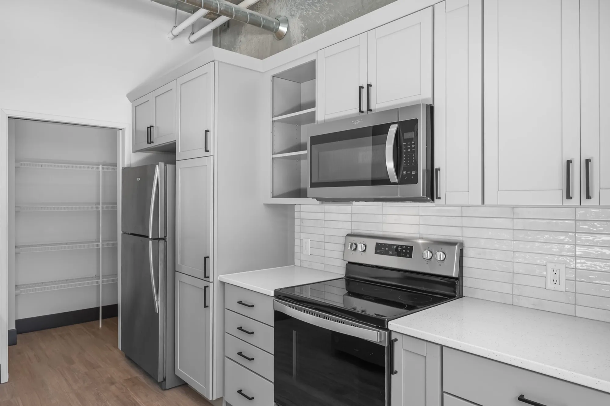 Modern kitchen featuring sleek stainless steel appliances, elegant white cabinetry, and a spacious pantry.