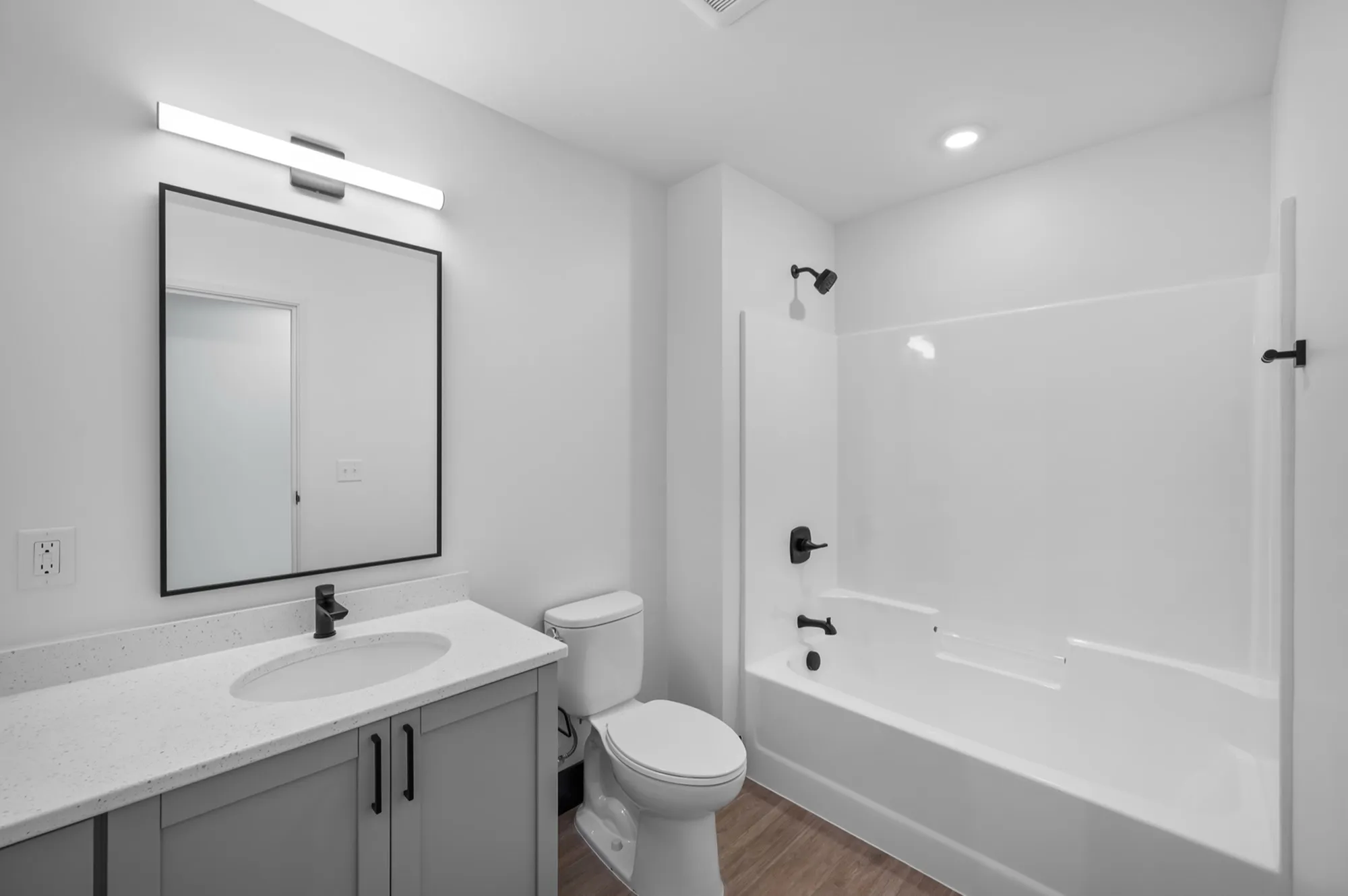 Elegant modern bathroom with sleek fixtures, a large mirror, and a pristine shower-tub combo.