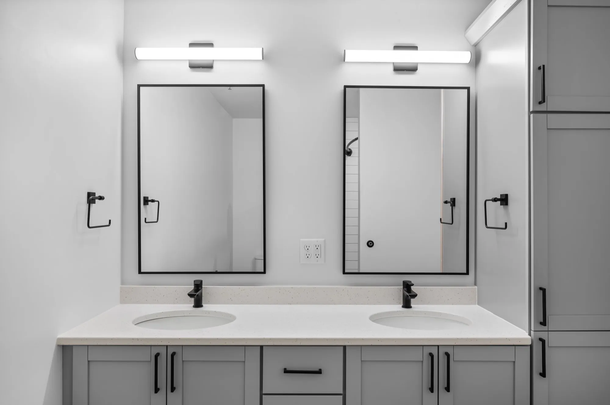 Modern bathroom showcasing a sleek double vanity with black fixtures, elegant mirrors, and ample storage.