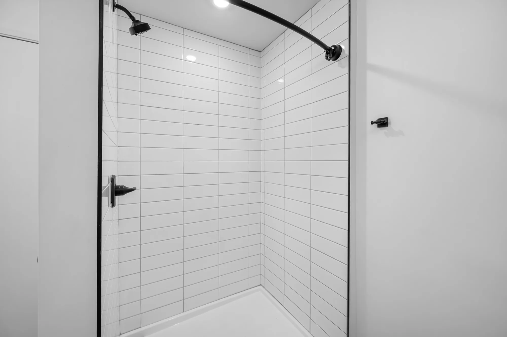Elegant modern shower with sleek white subway tiles and contemporary black fixtures.