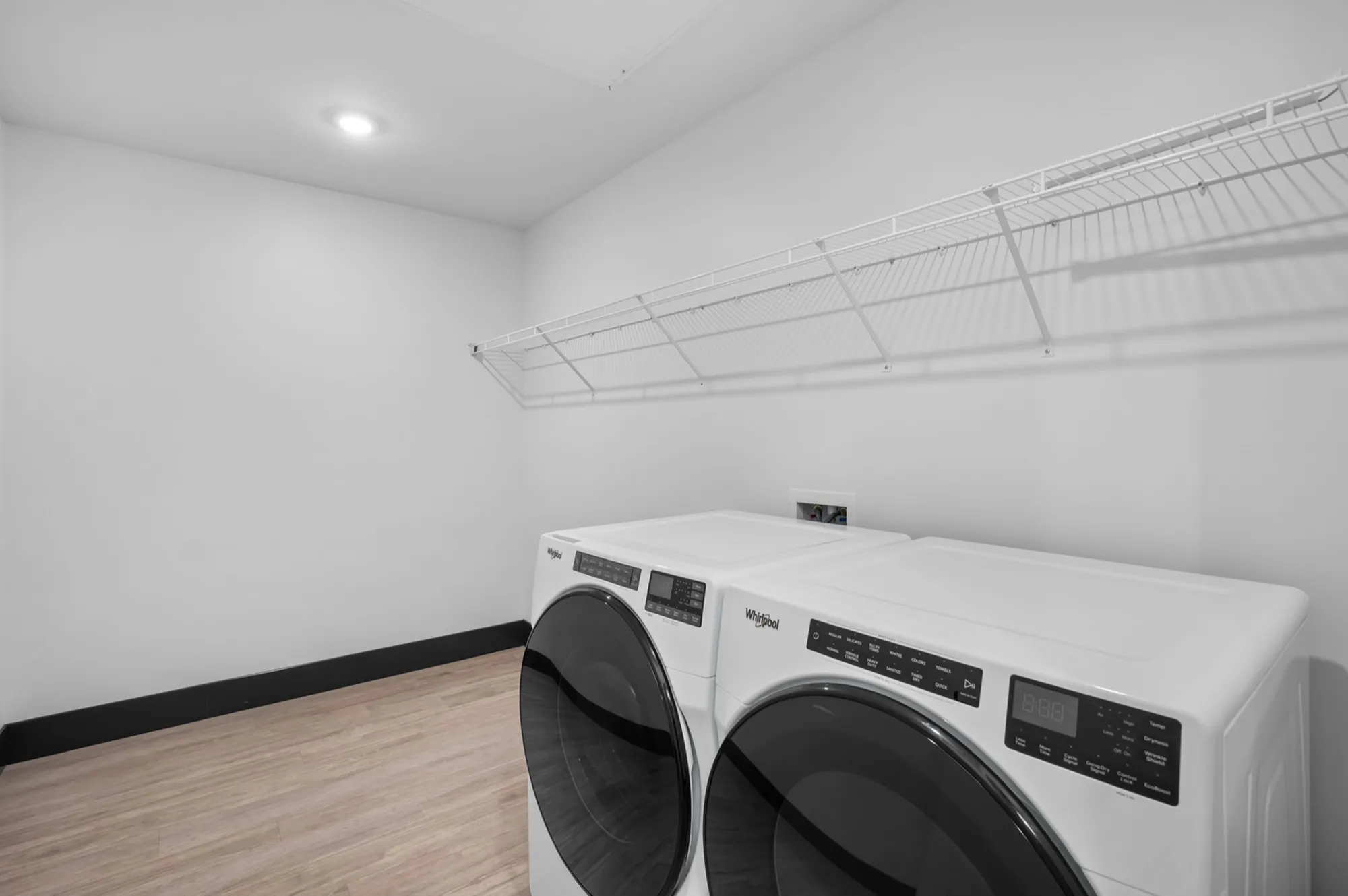 Modern laundry room with sleek washer and dryer, featuring ample shelving and clean design.