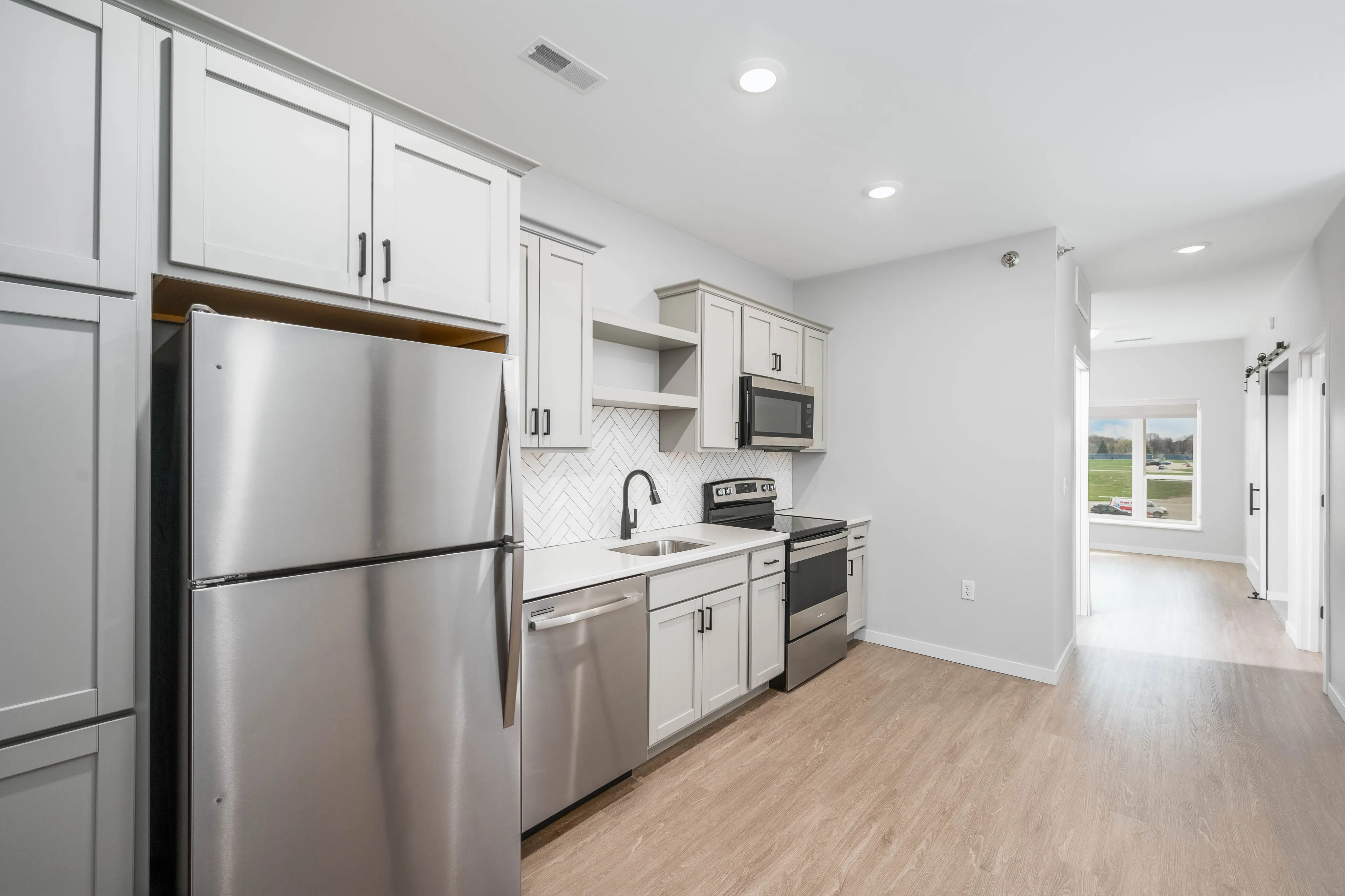 Modern kitchen with stainless steel appliances, elegant cabinetry, and a bright window view in a stylish apartment.