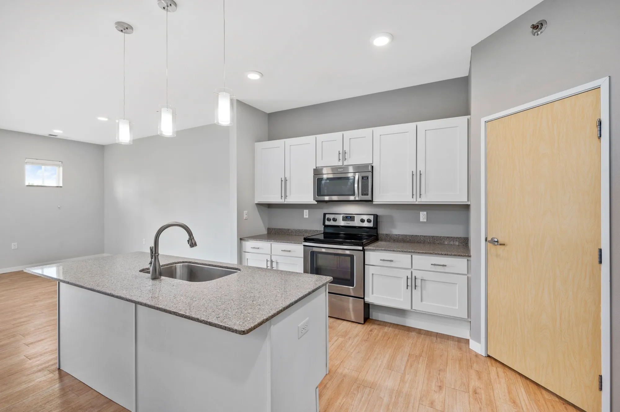 Modern kitchen with sleek countertops, stainless steel appliances, and elegant pendant lighting, perfect for culinary enthusiasts.