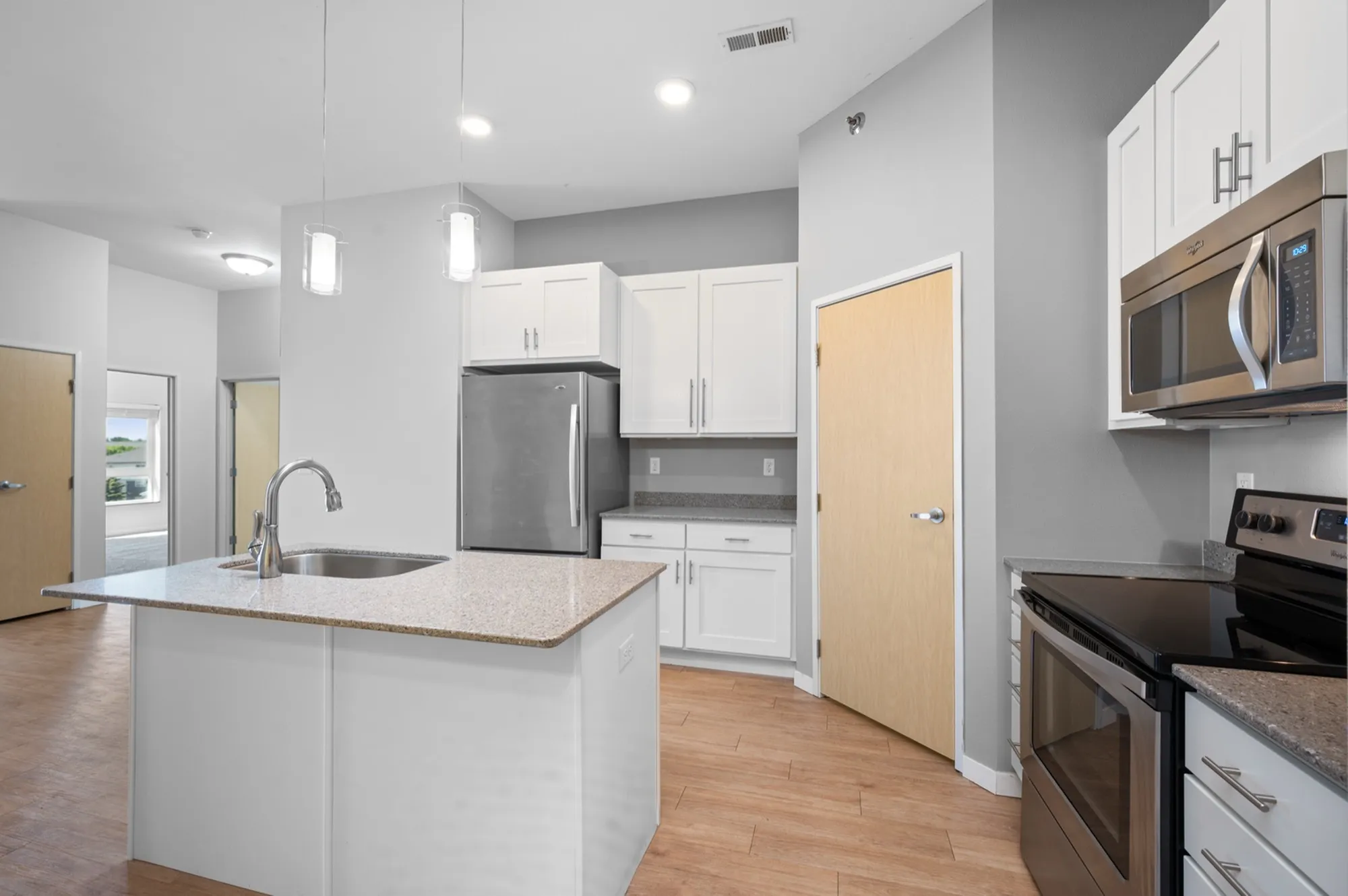 Modern kitchen with sleek stainless steel appliances, elegant granite countertops, and stylish pendant lighting.