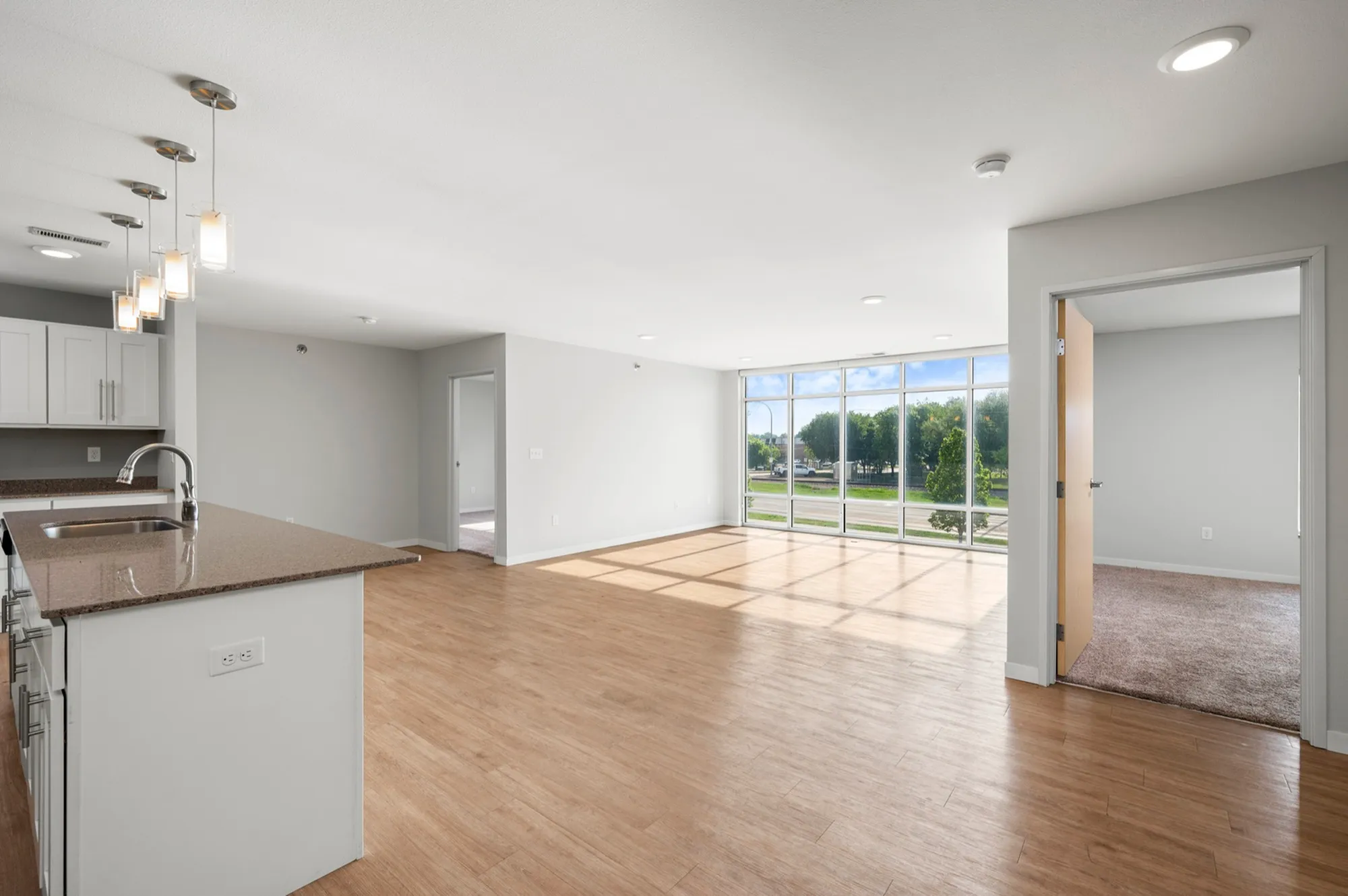 Modern open-concept apartment with sleek kitchen island, large windows, and inviting hardwood floors.