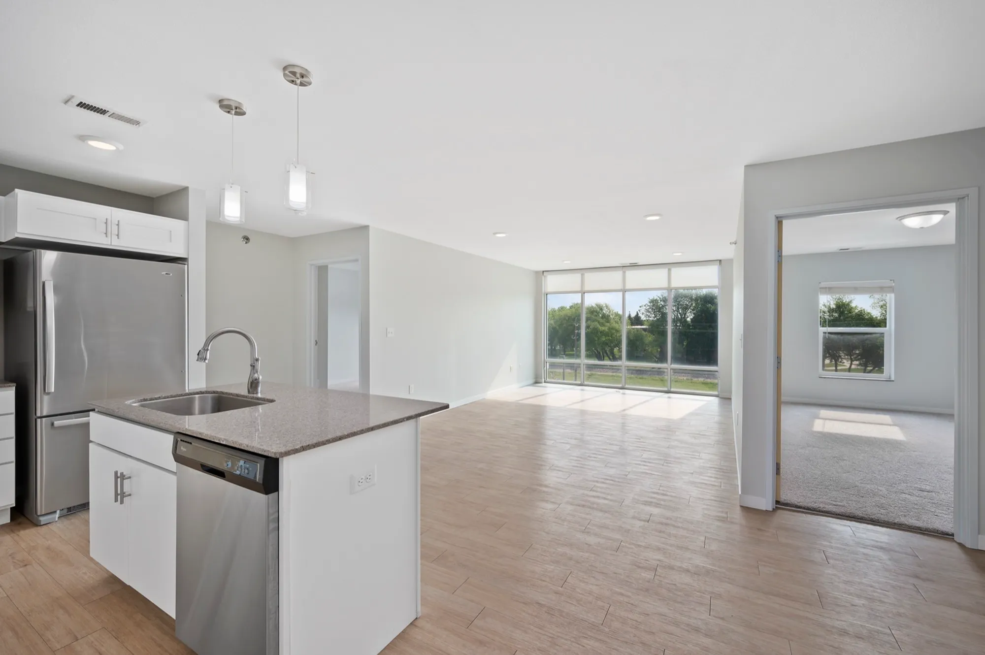 Bright and airy open-plan apartment featuring a modern kitchen with stainless steel appliances, spacious living area, and floor-to-ceiling windows offering scenic views.