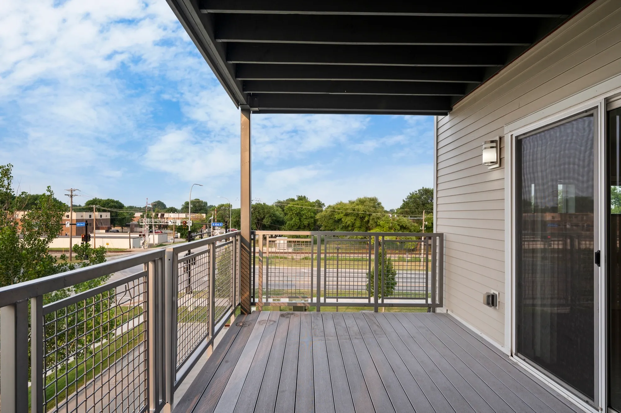 Modern apartment balcony with sleek railing overlooking a vibrant urban neighborhood, perfect for relaxing or entertaining.