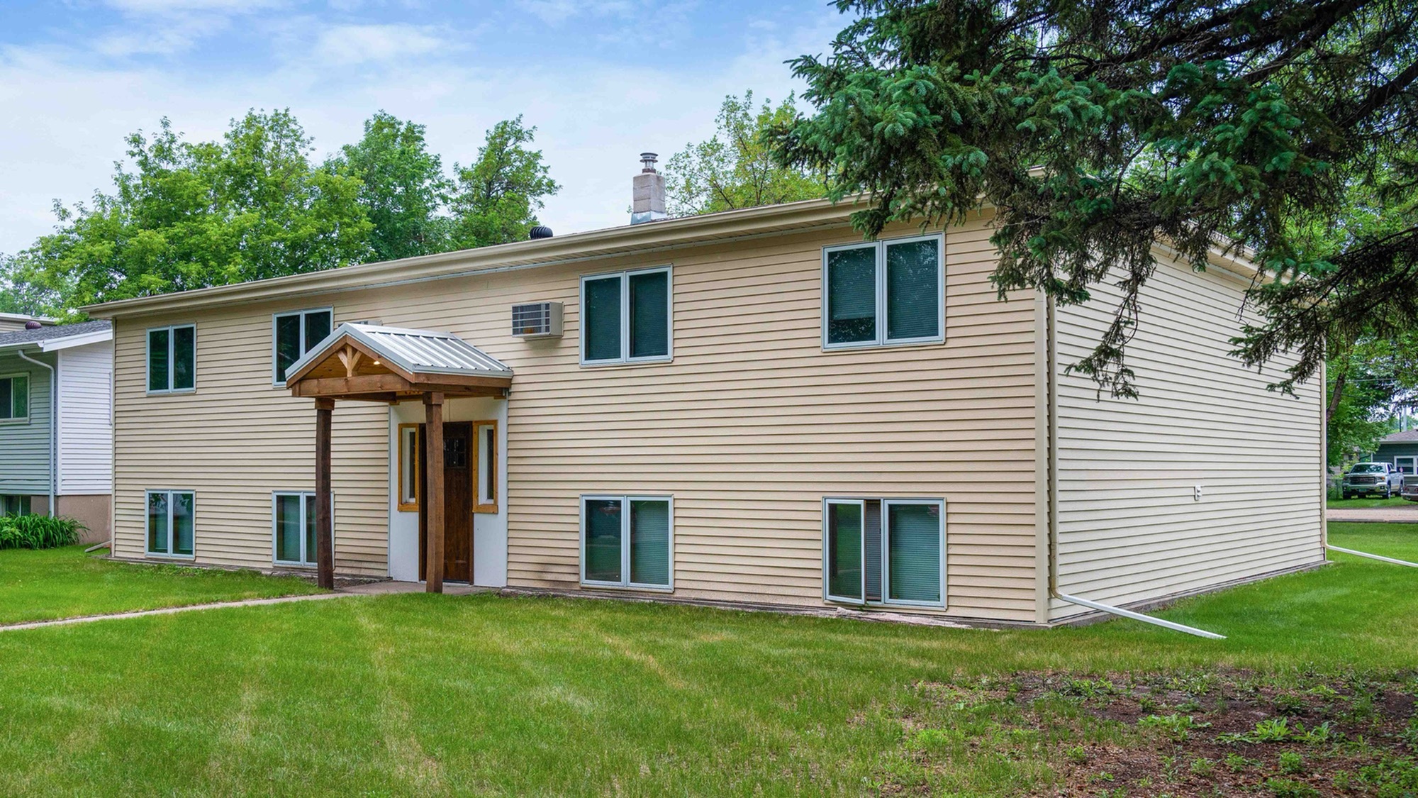 Charming suburban home with beige siding, lush green lawn, and mature trees creating a peaceful atmosphere.
