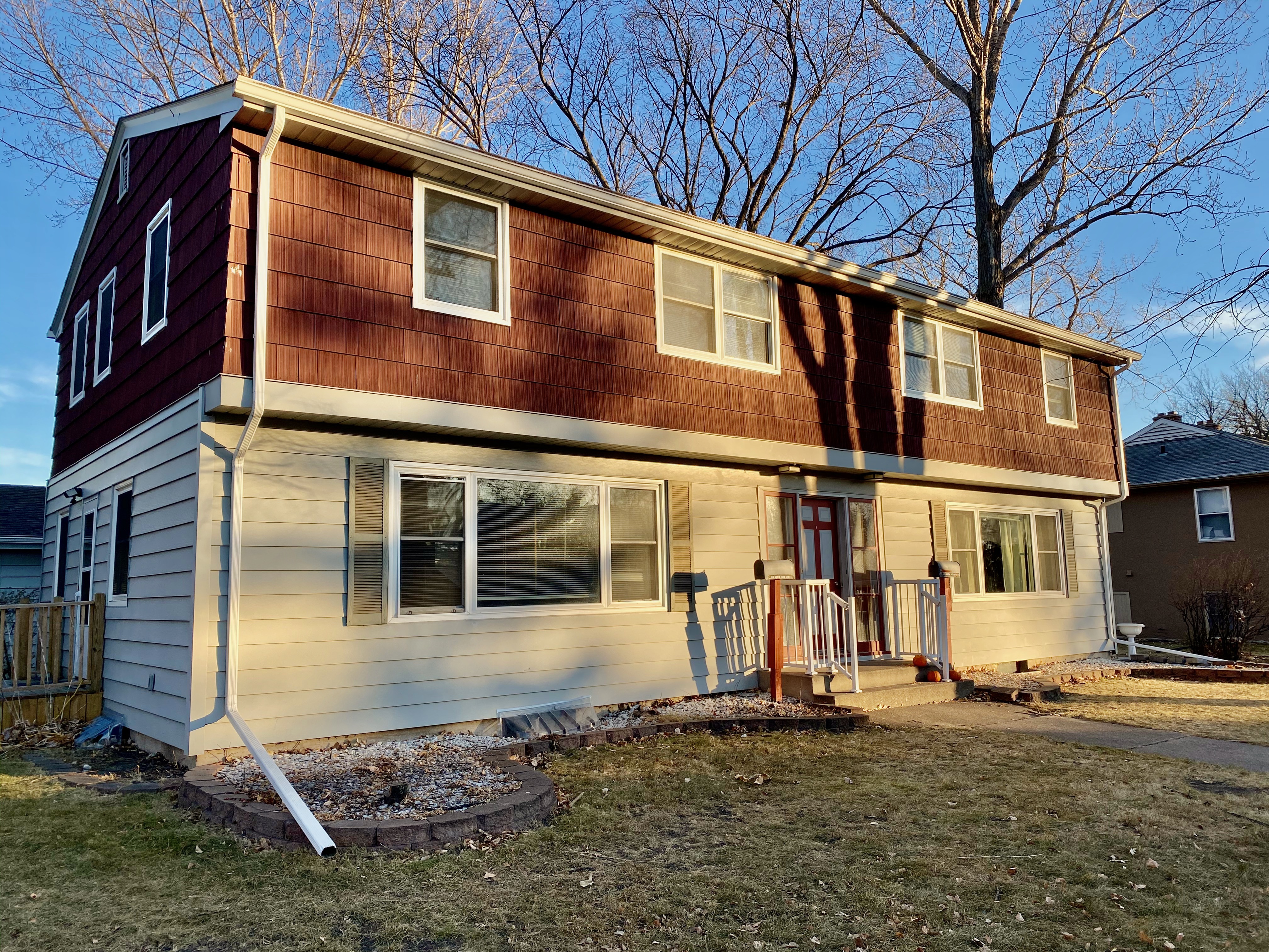 Charming two-story house with warm wooden accents and welcoming front porch, set in a tranquil suburban neighborhood.
