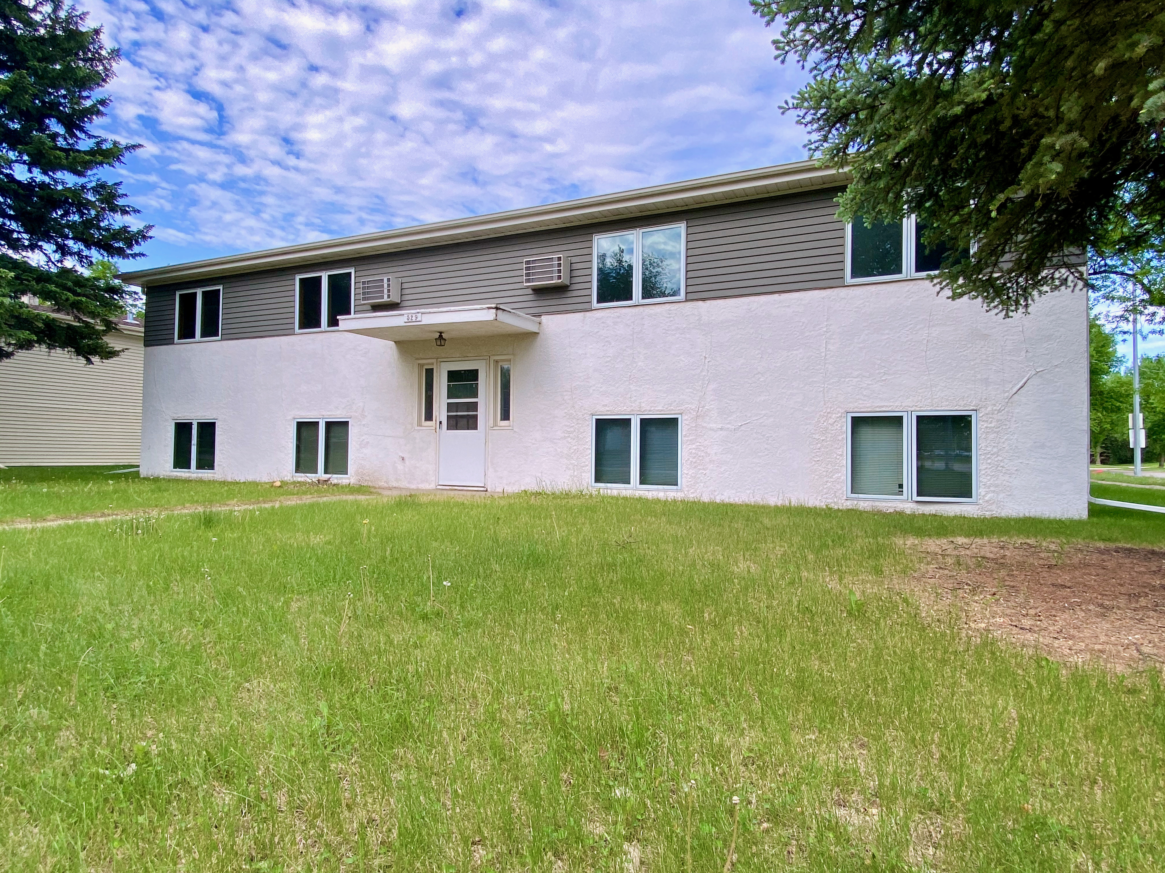 Charming suburban apartment building with a lush green lawn and a welcoming entrance.