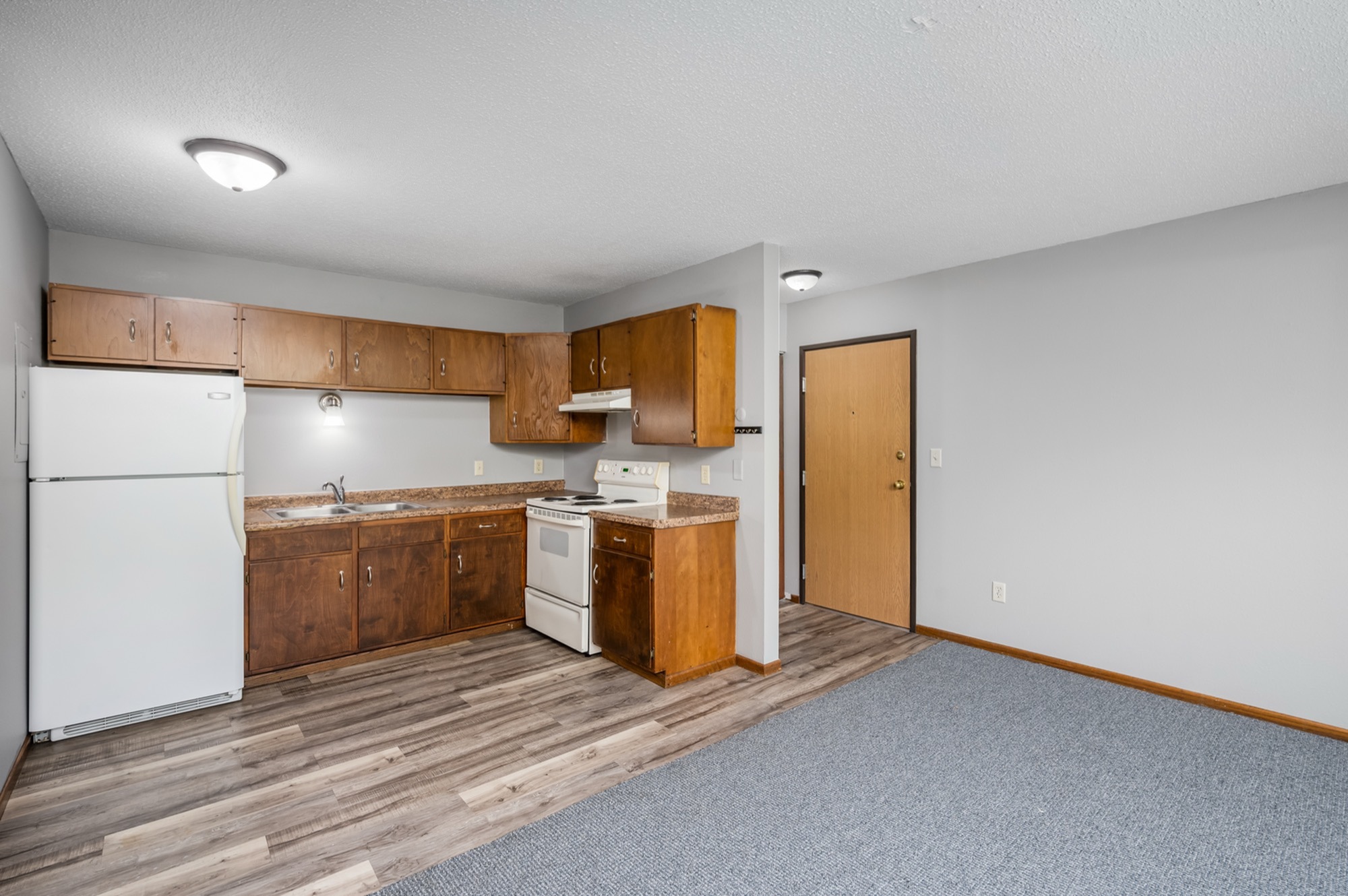 Inviting kitchen space with warm wooden cabinetry, sleek countertops, and modern appliances adjacent to cozy living area.