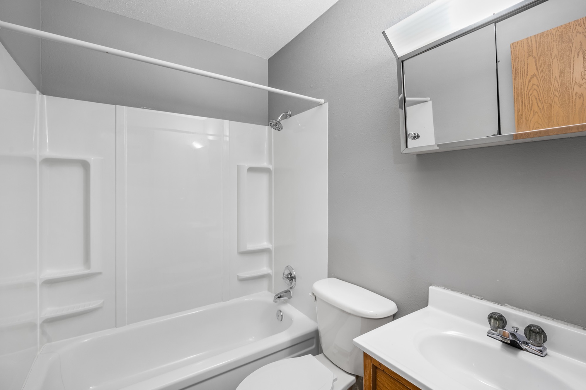 Modern bathroom with sleek fixtures, featuring a bright white bathtub, convenient showerhead, and stylish vanity with mirror.