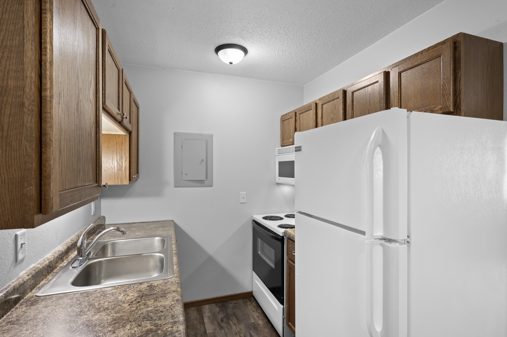 Inviting kitchen space with sleek countertops, dual sinks, and abundant wooden cabinetry for stylish functionality.