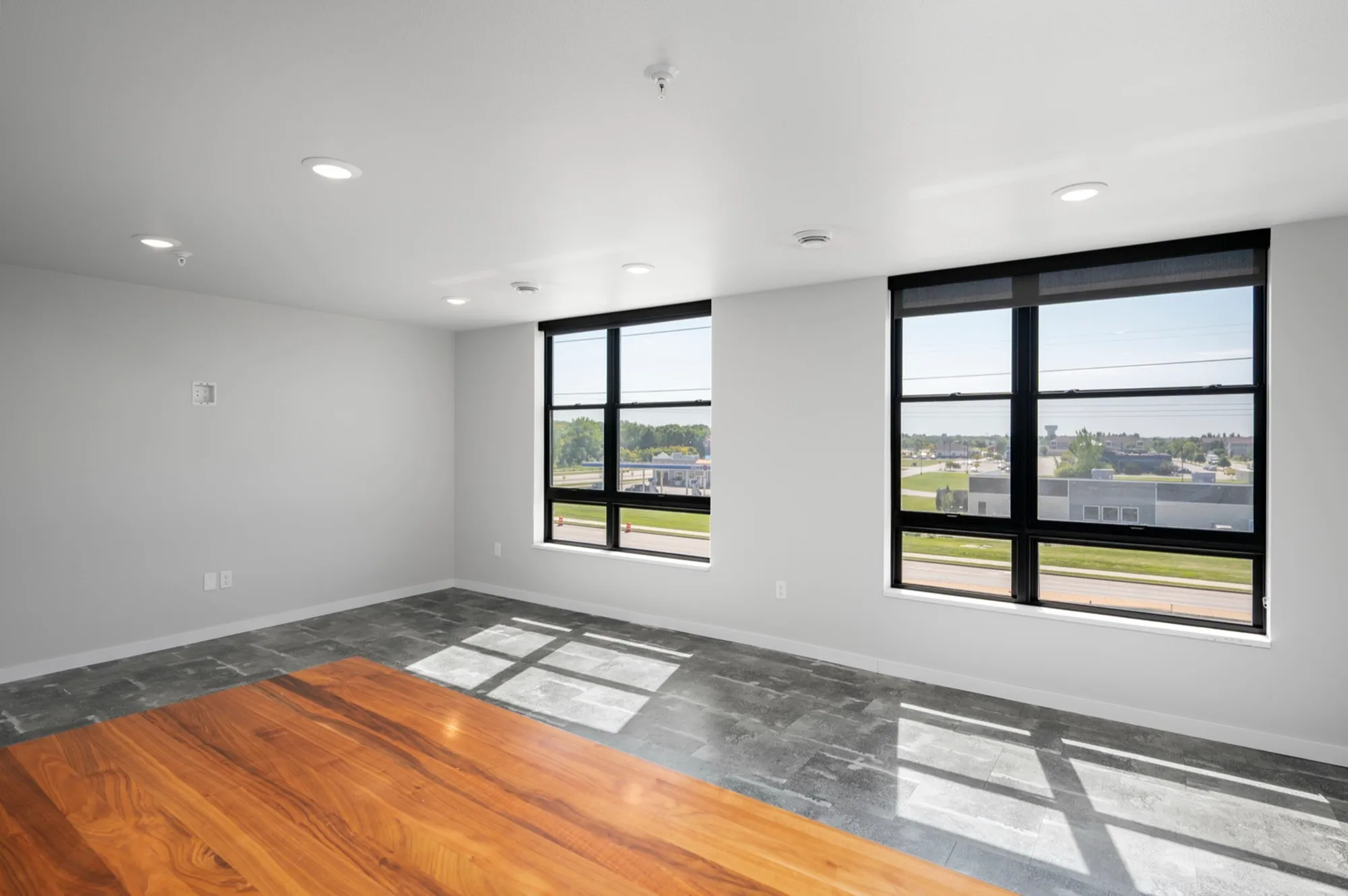 Bright and spacious living area with large windows offering scenic views, featuring modern flooring and a fresh, contemporary design.