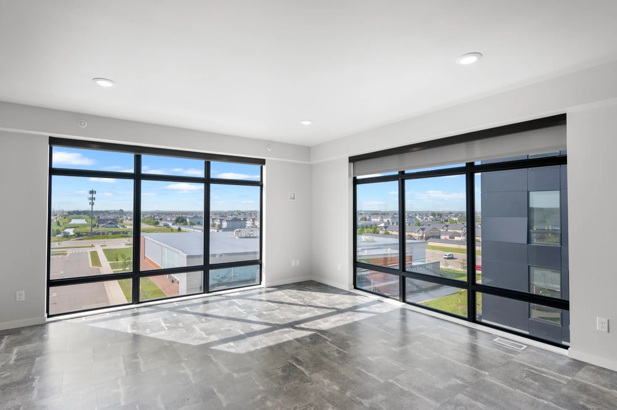 Bright, spacious room with floor-to-ceiling windows offering a panoramic city view; perfect for modern living.