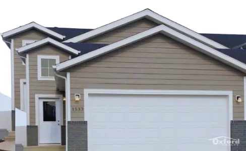 Charming two-story home with modern siding and a spacious white garage, perfect for a warm and welcoming family residence.