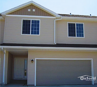 Charming townhouse exterior with inviting front entrance and modern garage by Oxford Realty.