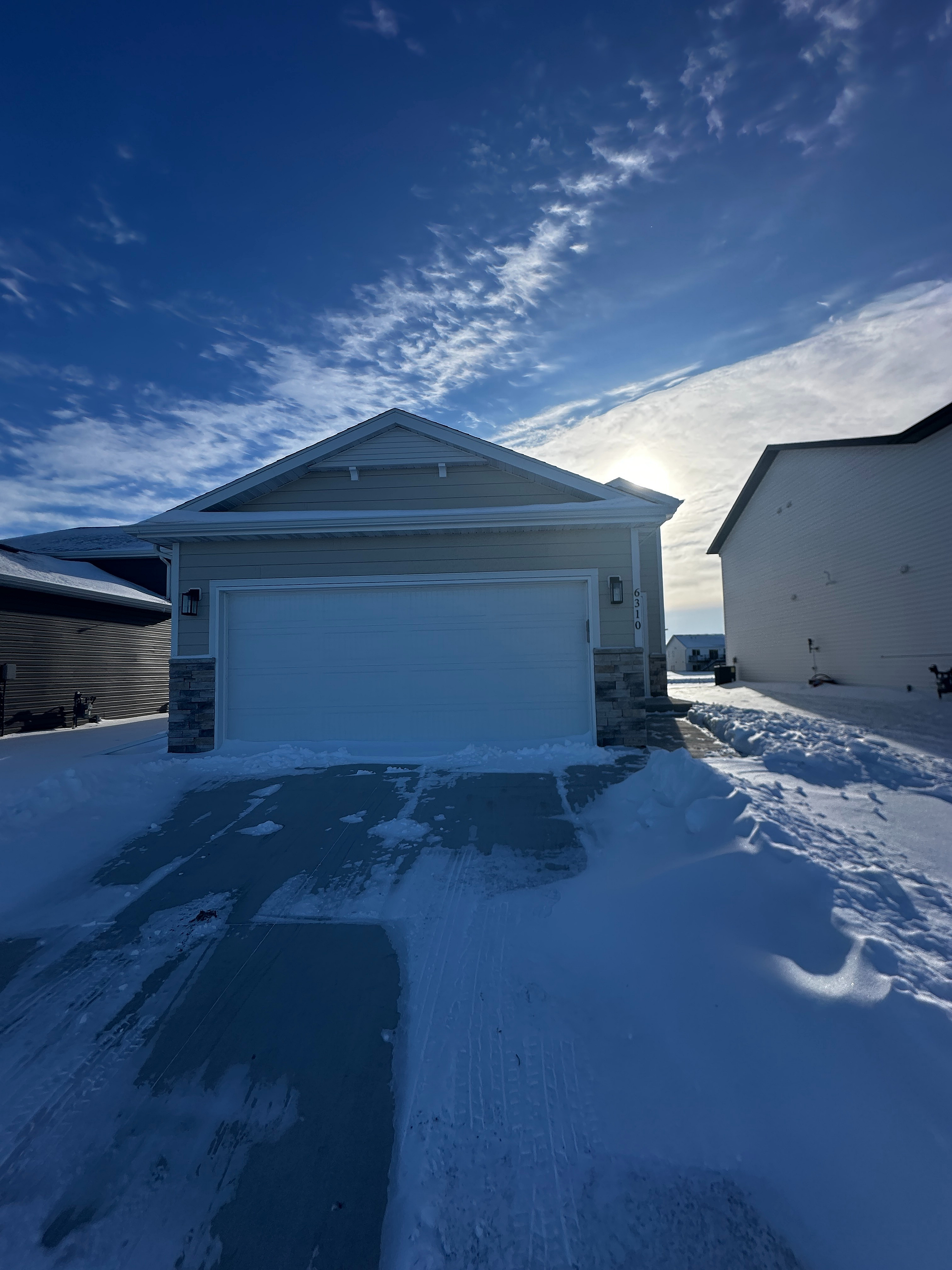 Charming single-story home with a two-car garage, set against a stunning winter sky.