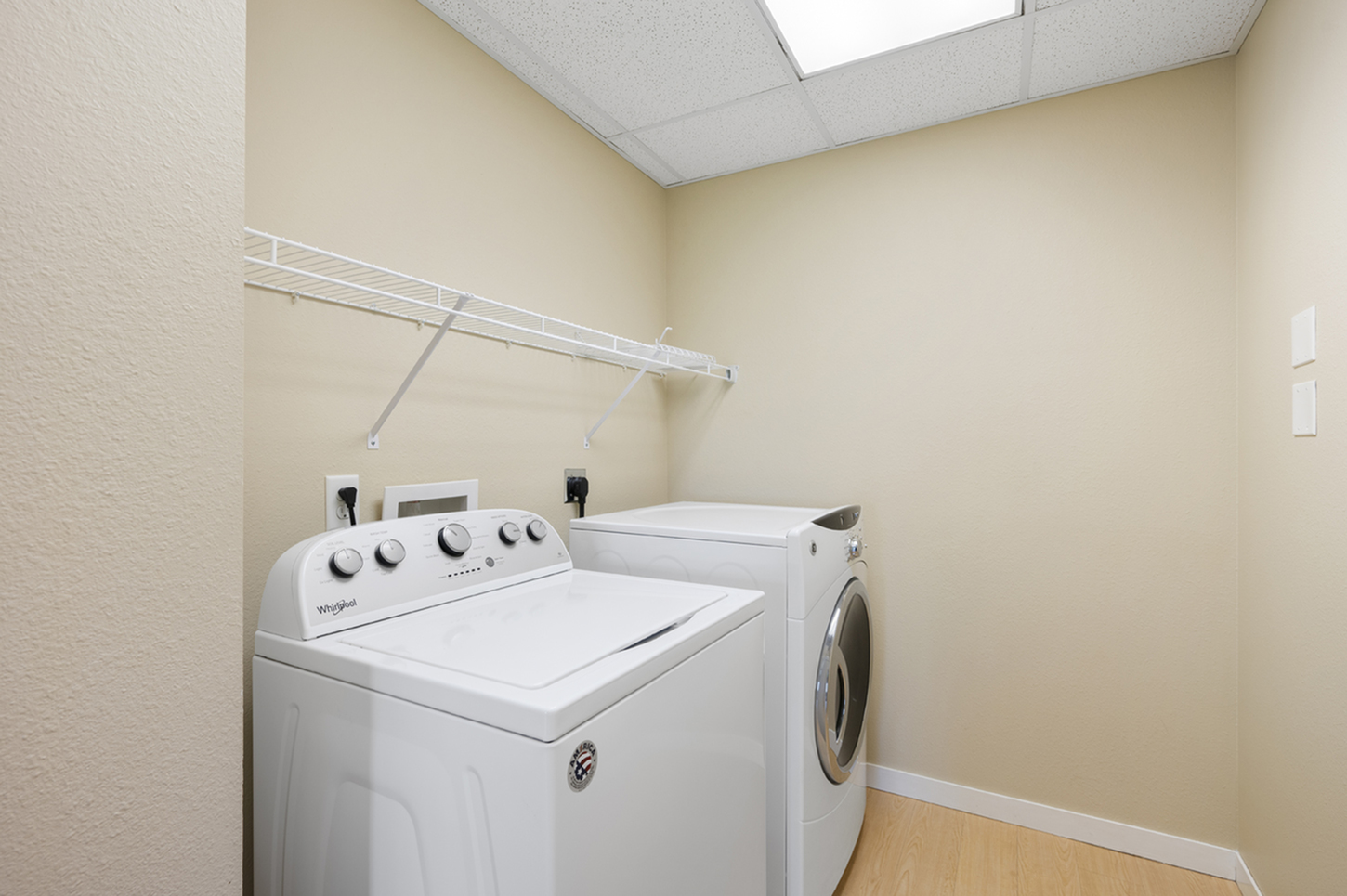 Modern laundry room with energy-efficient washer and dryer, featuring sleek shelving and warm beige walls.
