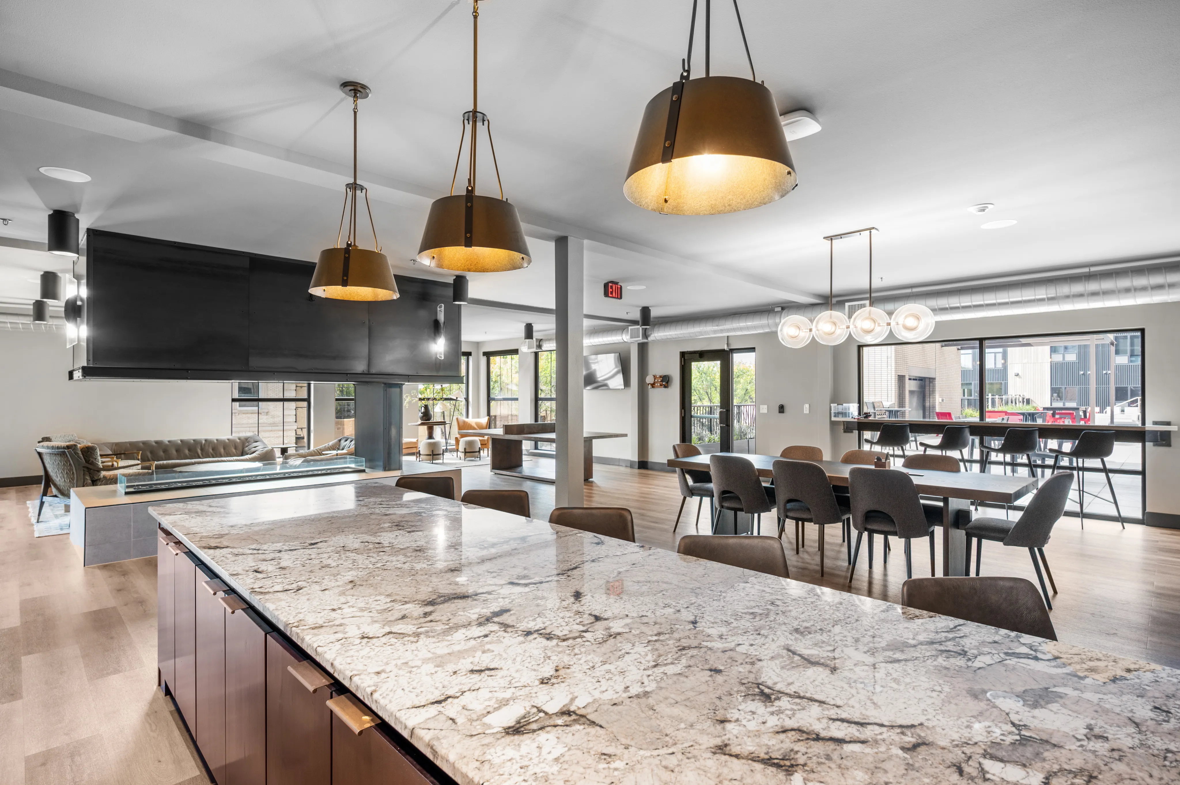 Luxurious open-concept dining and living area featuring elegant pendant lighting, a marble countertop, and modern decor with large windows allowing ample natural light.