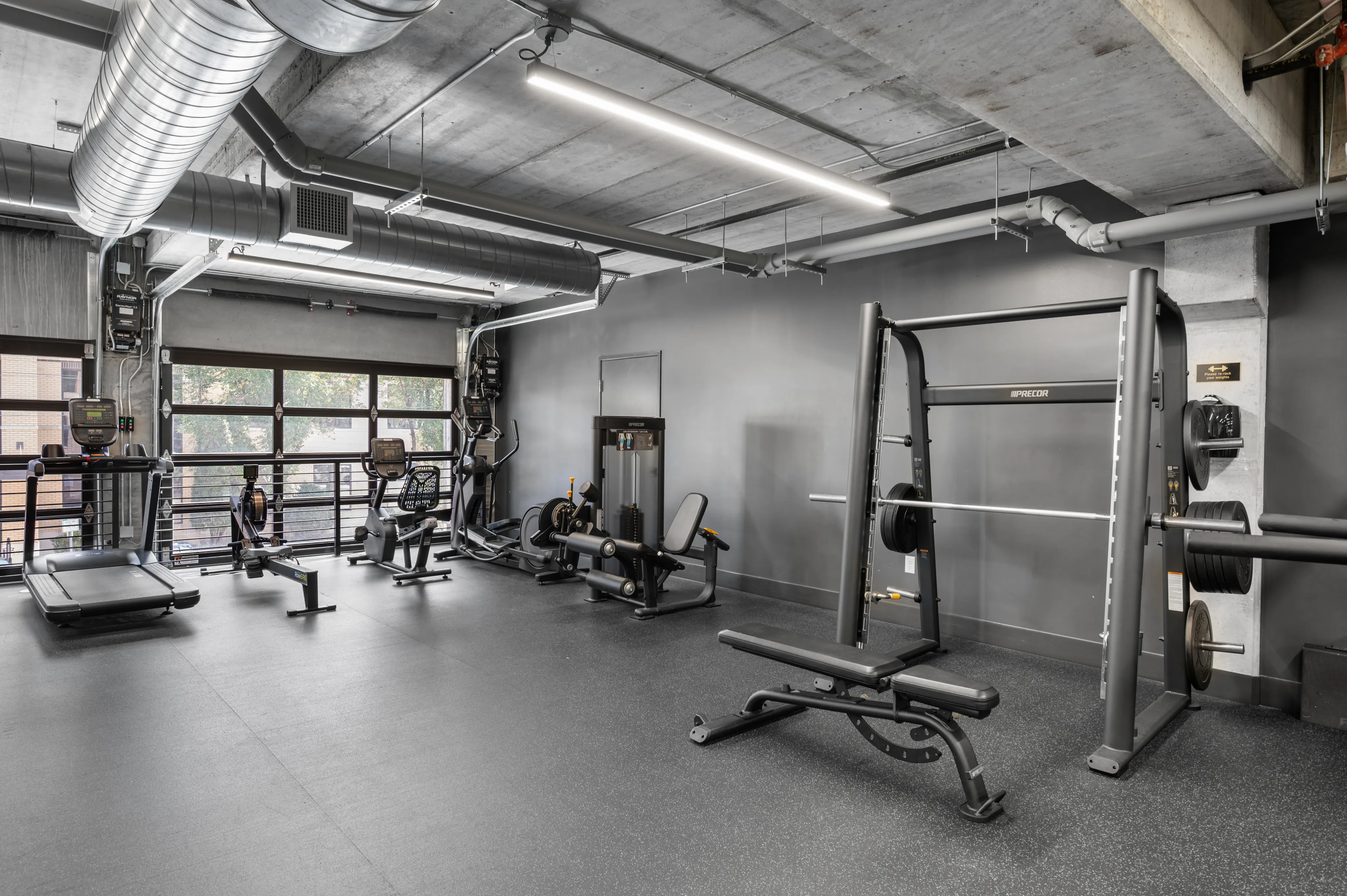 Modern fitness center featuring state-of-the-art gym equipment, including treadmills, row machines, and weightlifting stations, in an industrial chic setting.