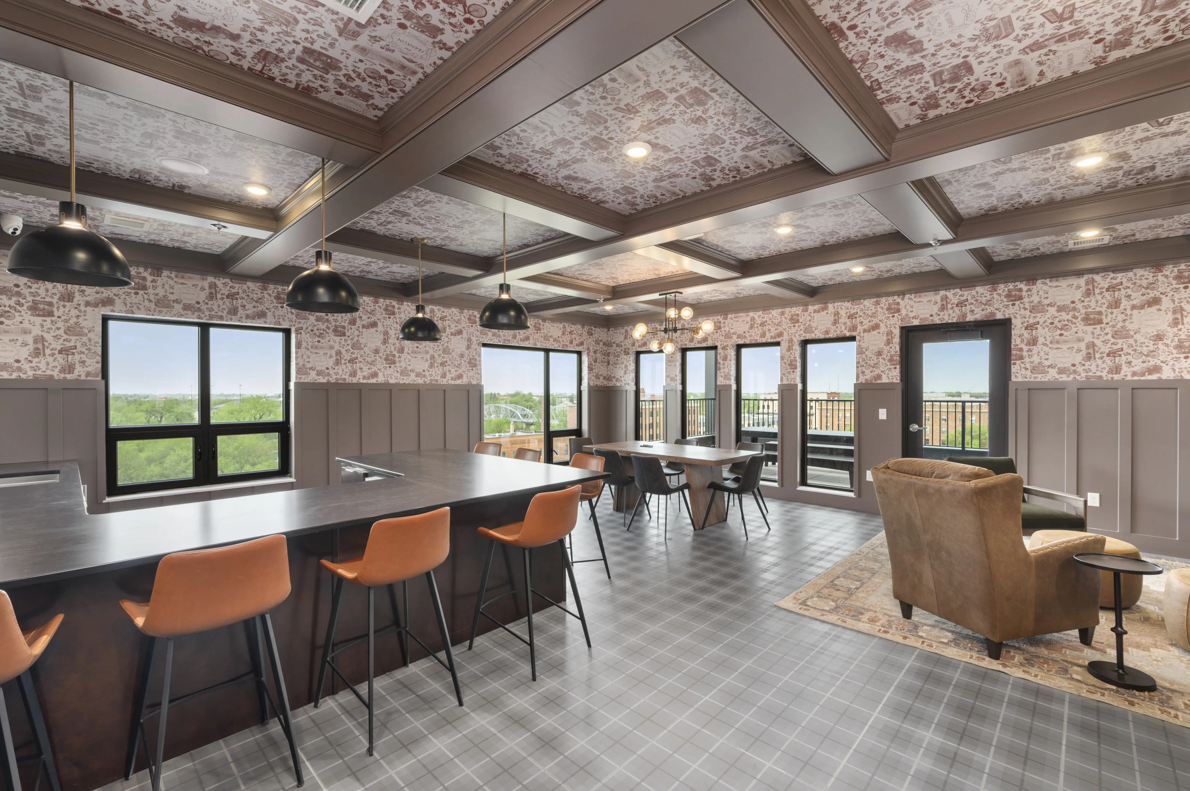 Elegant communal dining area with chic pendant lights, modern bar seating, and large windows offering scenic views.