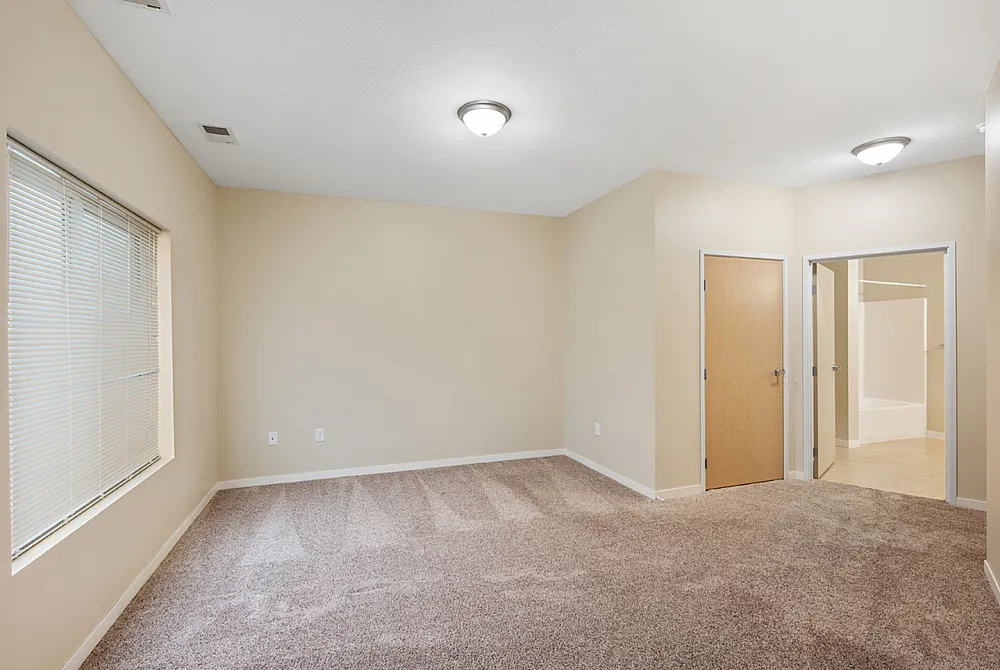 Inviting bedroom featuring soft carpeting, ample natural light from large windows, and modern lighting fixtures for a cozy ambiance.