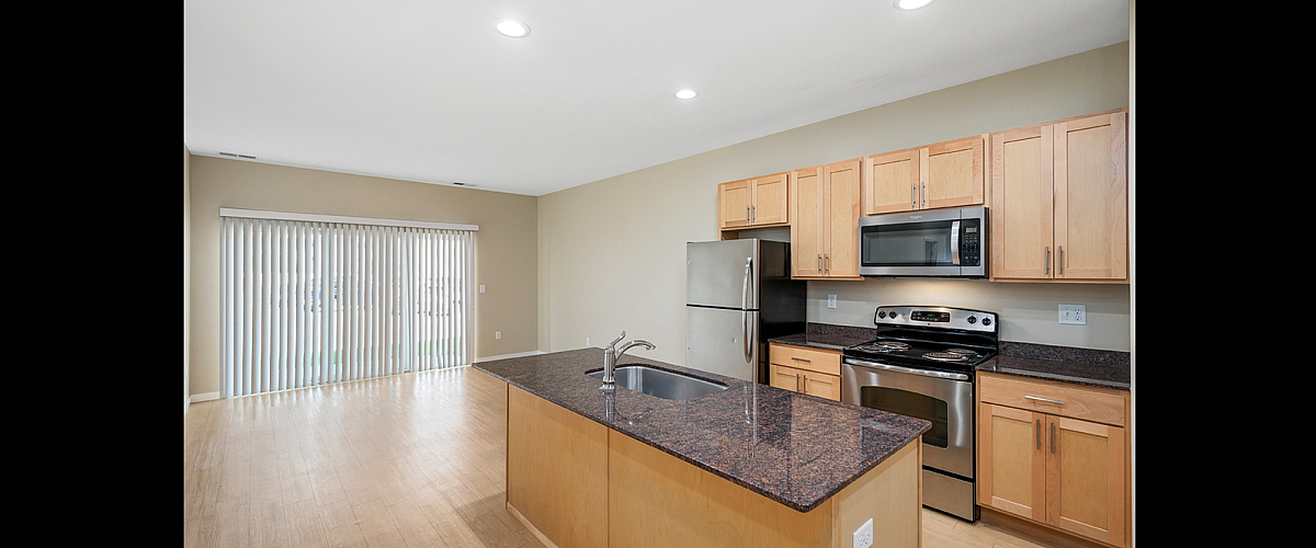 Bright and modern kitchen with sleek stainless steel appliances and elegant granite countertops in an open-concept design.