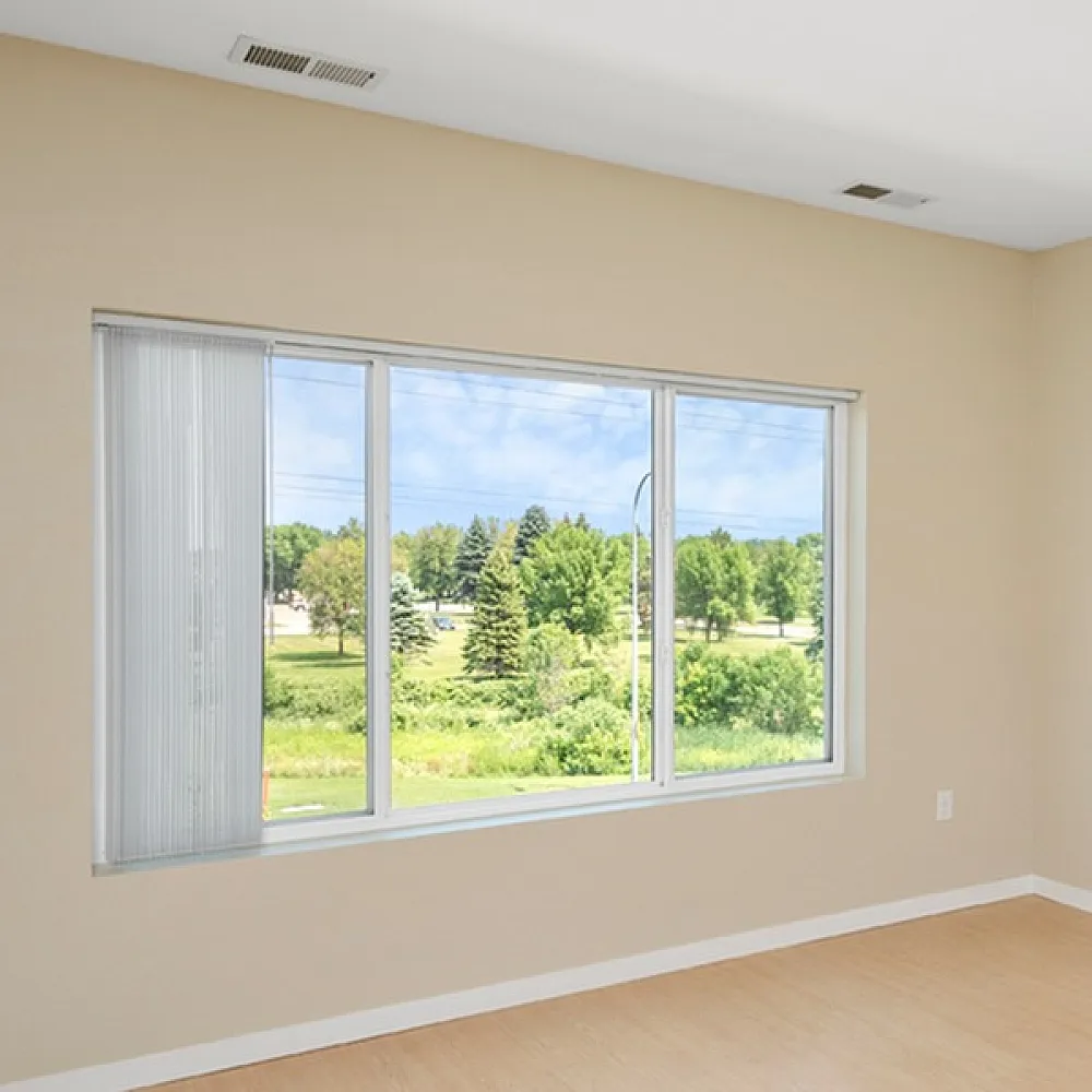 Bright and airy room with large window offering scenic views of lush greenery, neutral walls, and stylish wood flooring.