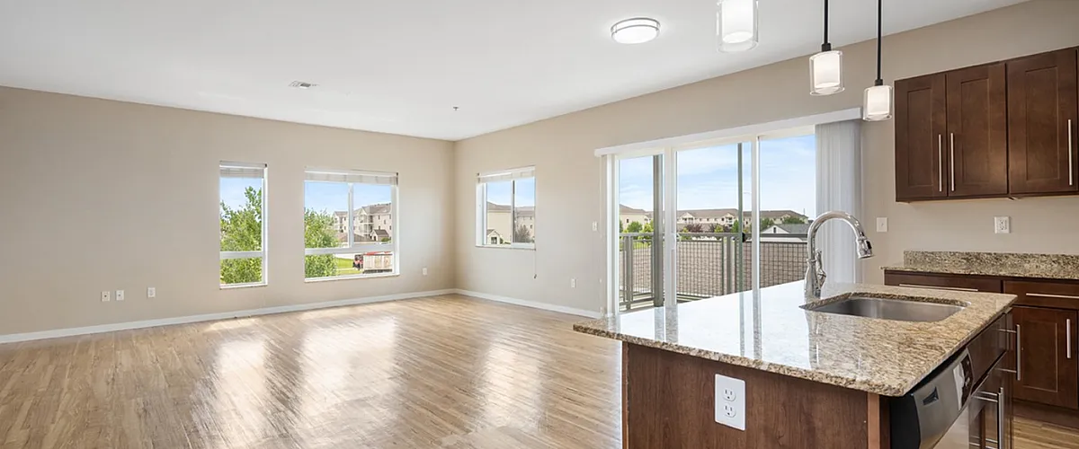 Inviting open-plan living area with hardwood floors, modern kitchen island, and large windows offering abundant natural light.