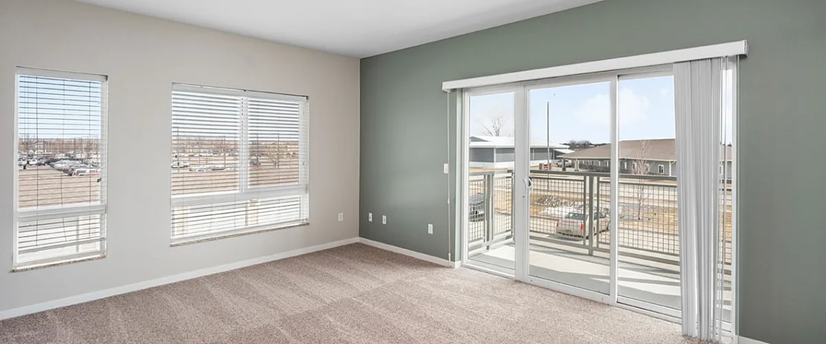 Bright and airy living room featuring large windows with scenic views, plush carpeting, and access to a charming balcony.
