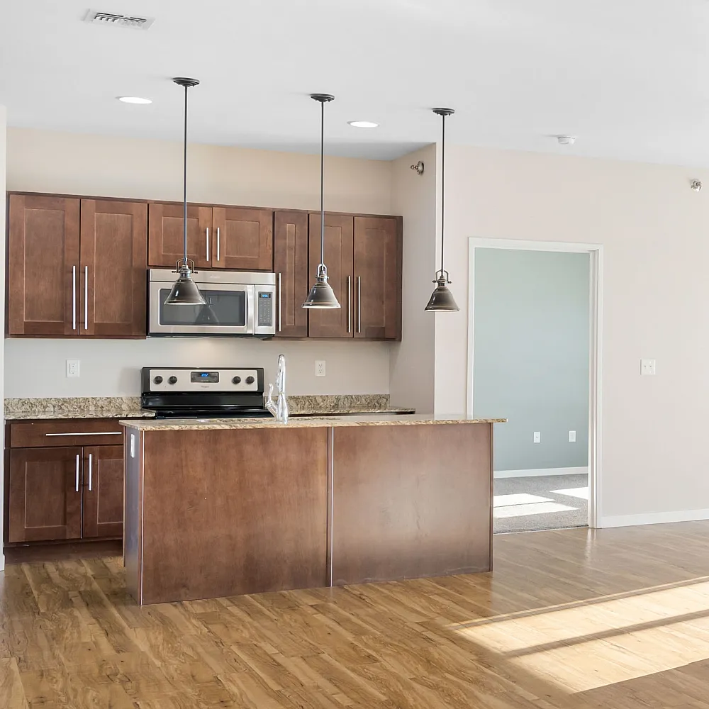 Bright open-concept kitchen with modern wooden cabinets, sleek pendant lighting, and elegant hardwood flooring.