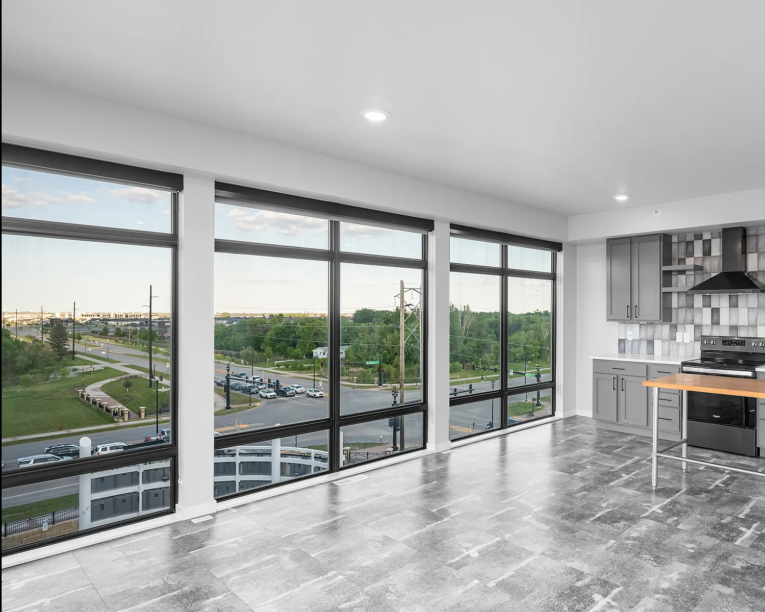 Modern kitchen with sleek gray cabinetry, gas range, and large windows offering panoramic city views.