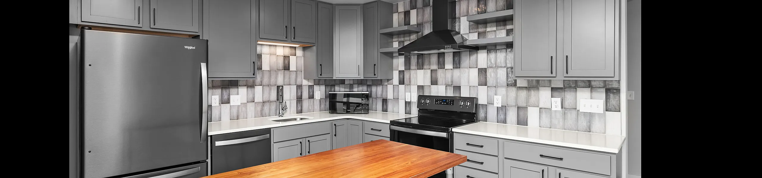 Modern kitchen with sleek gray cabinets, stainless steel appliances, and a stylish wooden island.