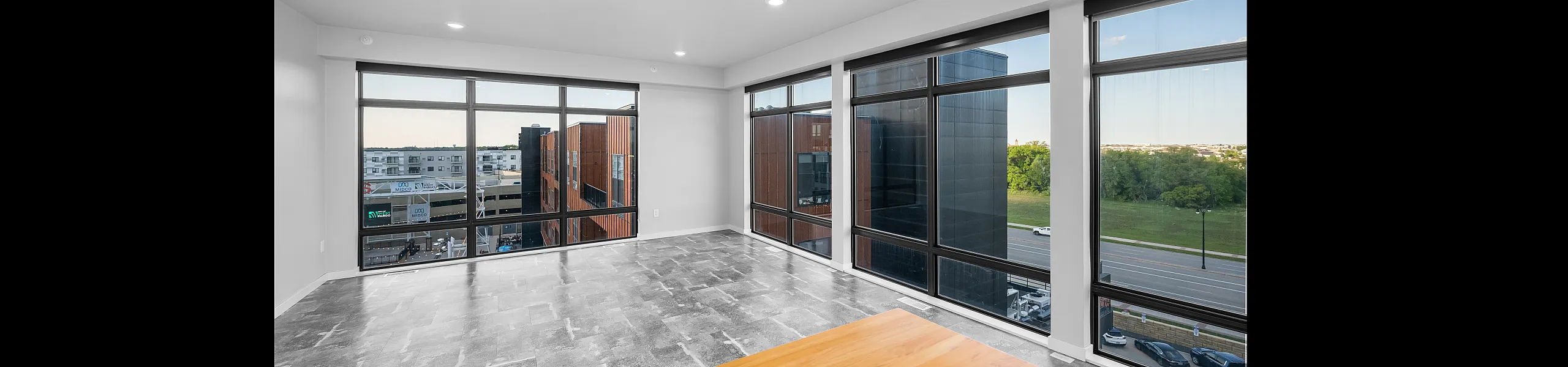 Modern apartment with expansive windows showcasing a stunning urban view, offering abundant natural light and sleek grey tiling.