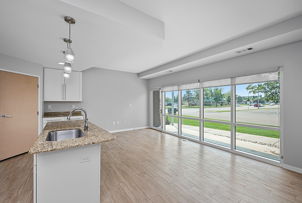 Modern apartment interior featuring spacious open floor plan, elegant kitchen island, and expansive windows with outdoor views.