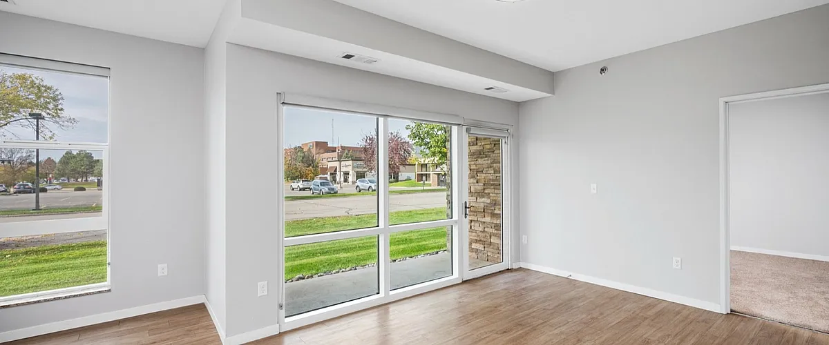 Bright modern apartment with large windows, elegant wooden floors, and a serene view, perfect for a cozy and inviting living space.