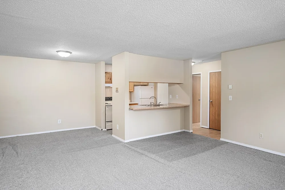 Inviting open-floor layout featuring plush carpeting, a cozy kitchen with a breakfast bar, and neutral tones creating a warm atmosphere.