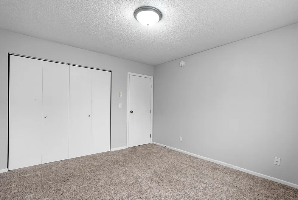 Bright, modern bedroom with plush carpeting and spacious closet, perfect for personalization.