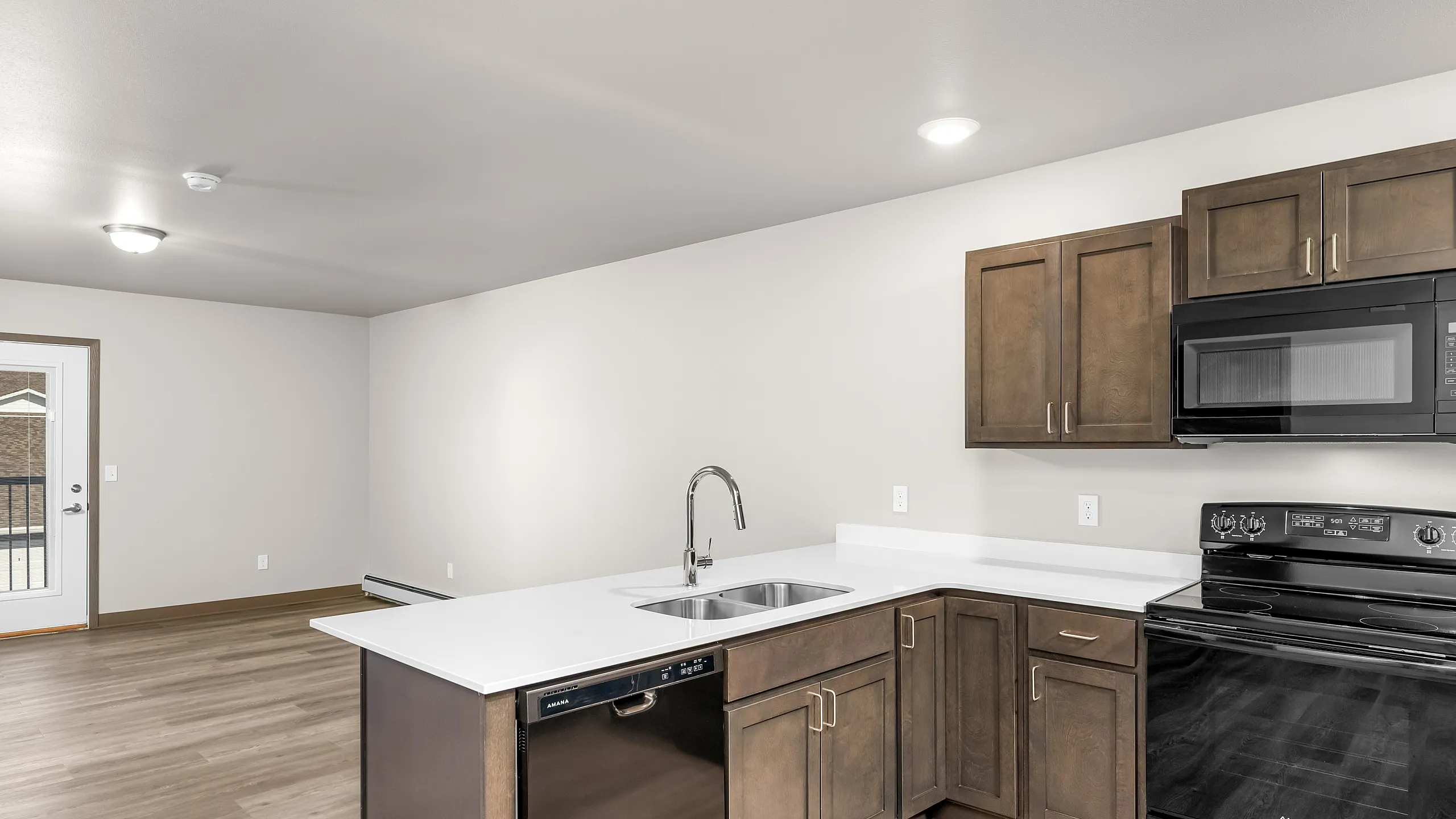 Modern open-concept kitchen featuring sleek countertops, elegant wood cabinetry, and stylish black appliances, perfect for contemporary living.