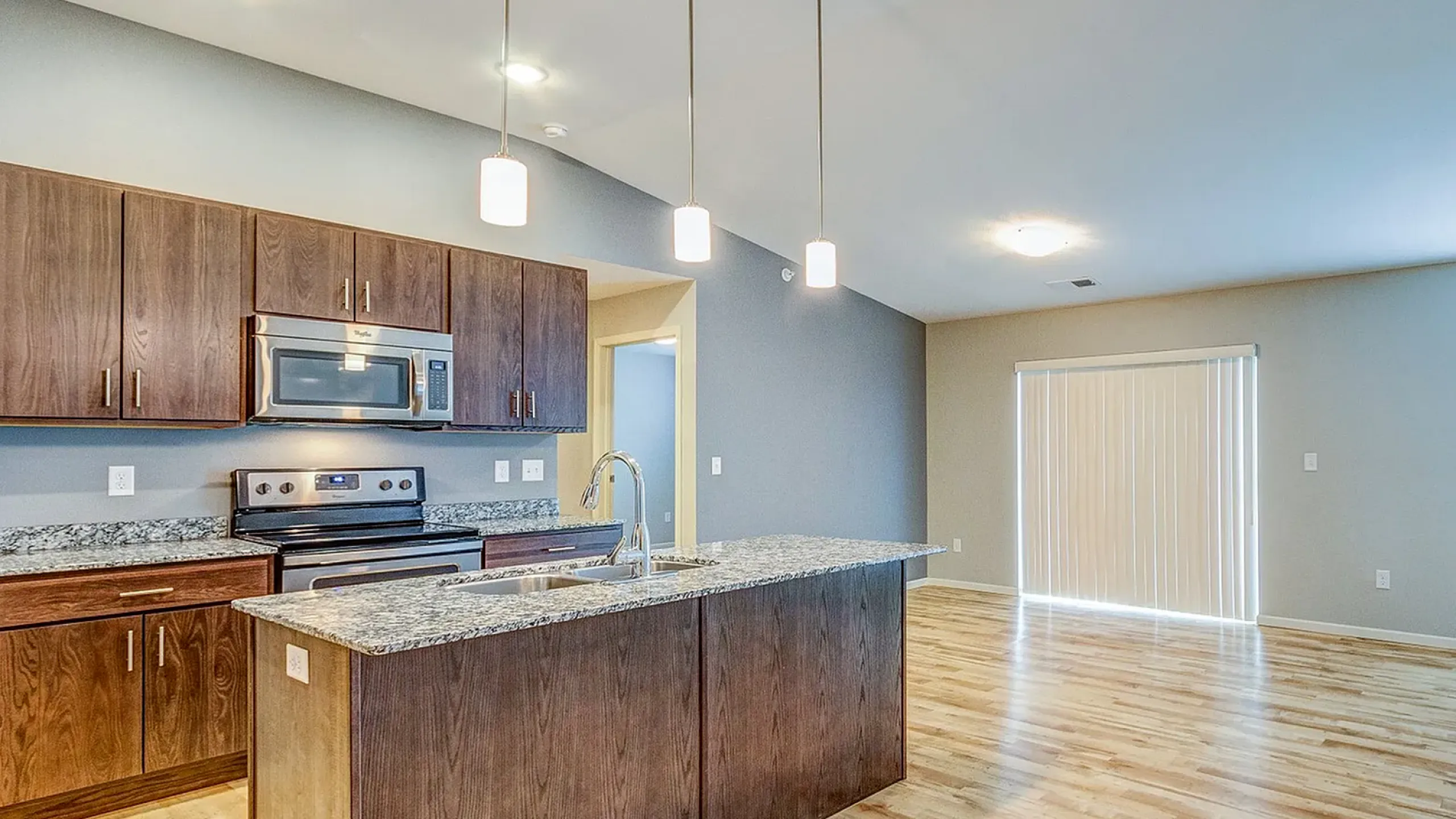 Modern open-concept kitchen with sleek granite countertops, elegant pendant lighting, and spacious living area with abundant natural light.