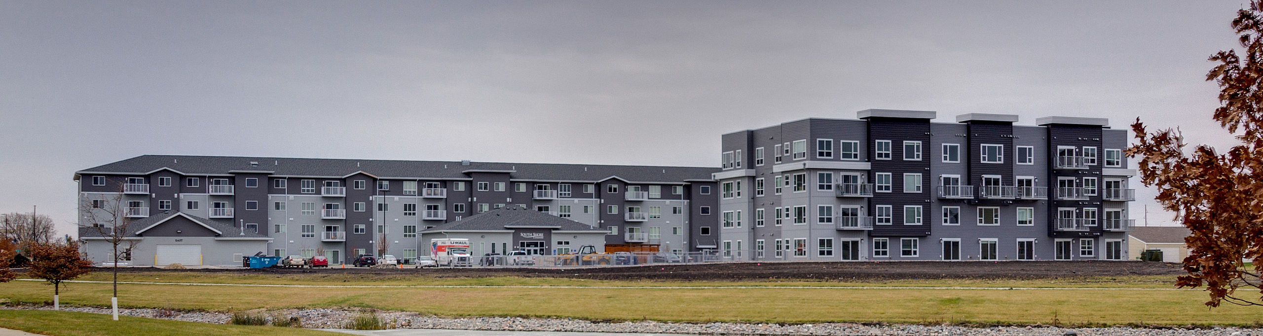 Elegant modern apartment complex with scenic views, featuring a charming pathway and lush green surroundings.